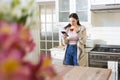 Focused caucasian woman standing, holding tea cup, using smartphone in kitchen at home, copy space Royalty Free Stock Photo