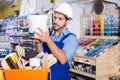 Focused workman choosing materials for renovation works in paint store