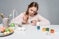 Focused child painting easter eggs at table