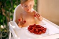 Focused child puts raspberries on fingers