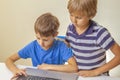 Focused child typing laptop computer and other kid help him. School, learning, e-learning concept Royalty Free Stock Photo
