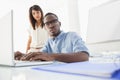 Focused coworkers using laptop and looking at camera