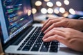 Focused Developer Typing Code on Laptop in Modern Office Environment at Night
