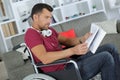 focused disabled man on wheelchair reading newspaper at home Royalty Free Stock Photo