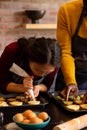 Focused diverse couple in aprons decorating christmas cookies in kitchen, copy space