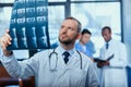 Focused doctor analyzing x-ray picture with colleagues behind