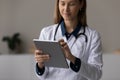 Focused doctor, physician using tablet computer, giving online virtual consultation