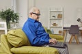 Focused elderly man sitting on sofa using laptop Royalty Free Stock Photo