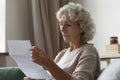 Concentrated mature woman read postal letter at home