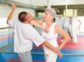 Elderly woman performing elbow strike and wristlock to man in self defense training Royalty Free Stock Photo