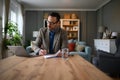 Focused elegant businessman signing documents while working over laptop on desk in home office Royalty Free Stock Photo