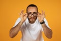 Focused european millennial bearded man in white t-shirt, meticulously adjusting his black-rimmed glasses