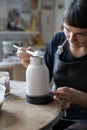 Focused European woman in apron restores ceramic vessel found during archaeological excavations