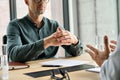 Focused businessman clasped hands sitting at table listening manager at meeting.