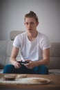 Focused expression of a man aged 20-29 with blond hair. The player sits on the couch in the living room and plays on the game Royalty Free Stock Photo