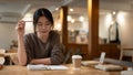 A focused female college student working remotely at a coffee shop, reading a book or doing homework Royalty Free Stock Photo