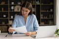 Focused female employee reading document, report, contract text