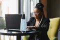 Focused female office worker using computer in coffee shop. African American business woman working on laptop in cafe and looking Royalty Free Stock Photo