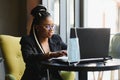 Focused female office worker using computer in coffee shop. African American business woman working on laptop in cafe and looking Royalty Free Stock Photo