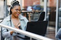 Focused female office worker using computer in coffee shop. African American business woman working on laptop in cafe and looking Royalty Free Stock Photo