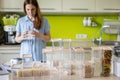 Focused female professional space organizer marking plastic case boxes for pasta storage at kitchen Royalty Free Stock Photo