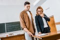 Focused female teacher helping male student with assignment during lesson