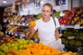 Focused fifteen-year-old girl chooses ripe oranges