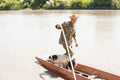 Focused fisherman with cute dog pushing off from pier with long stick, while sailing for fishing. Royalty Free Stock Photo