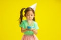 Focused Five Year Old Chinese Appearance Child in Party Hat Blow out Candles on Birthday Cake Holding it and Stands Royalty Free Stock Photo