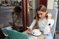 focused freelancer using smartphone near cup