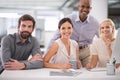 Focused on the future. a group of smiling businesspeople gathered at their desk.