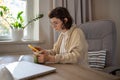 Focused girl freelancer browsing social networks looking in smartphone screen holding cup at home. Royalty Free Stock Photo