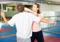 Girl performing elbow strike and wristlock to man in self defence training Royalty Free Stock Photo