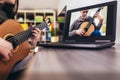 Girl playing acoustic guitar and watching online course on laptop while practicing at home. Online training, online Royalty Free Stock Photo