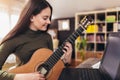 Girl playing acoustic guitar and watching online course on laptop while practicing at home. Online training, online Royalty Free Stock Photo