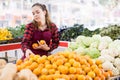 Focused girl salesperson in a store puts the tangerines on the counter