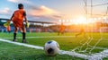 Focused goalkeeper in orange uniform preparing for soccer match at sunset. Royalty Free Stock Photo