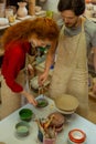 Focused good-looking couple using special paints and covering piece of clay