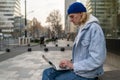 Focused guy freelancer doing urgent work on laptop on street sitting on bench in downtown.