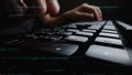 Focused Hands Typing on a Computer Keyboard with Code Overlay in a Dark Setting, Symbolizing Technology and Software Royalty Free Stock Photo