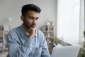 Focused handsome young Indian professional man working at computer