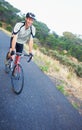 Focused on his ride. Shot of a lone rider cycling down a rural road with copy space.