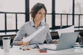 Focused hispanic woman worker analyzing documents and working on laptop computer in office Royalty Free Stock Photo