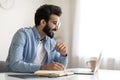 Focused indian man looking at laptop screen and writing in notebook Royalty Free Stock Photo