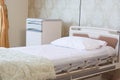 Focused indoors empty hospital room with comfortable bed with pillow in white satin and electrical support at day light Royalty Free Stock Photo