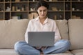 Focused Latin student girl using laptop on home couch