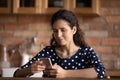 Focused Latin woman reading text on cellphone screen in kitchen