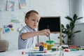 focused little boy with brush and paintings drawing picture alone