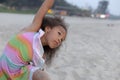 Focused little girl with dark skin is sitting on sand on beach, doing yoga exercise in morning. Royalty Free Stock Photo