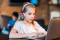 Focused little girl in headphones using laptop Royalty Free Stock Photo